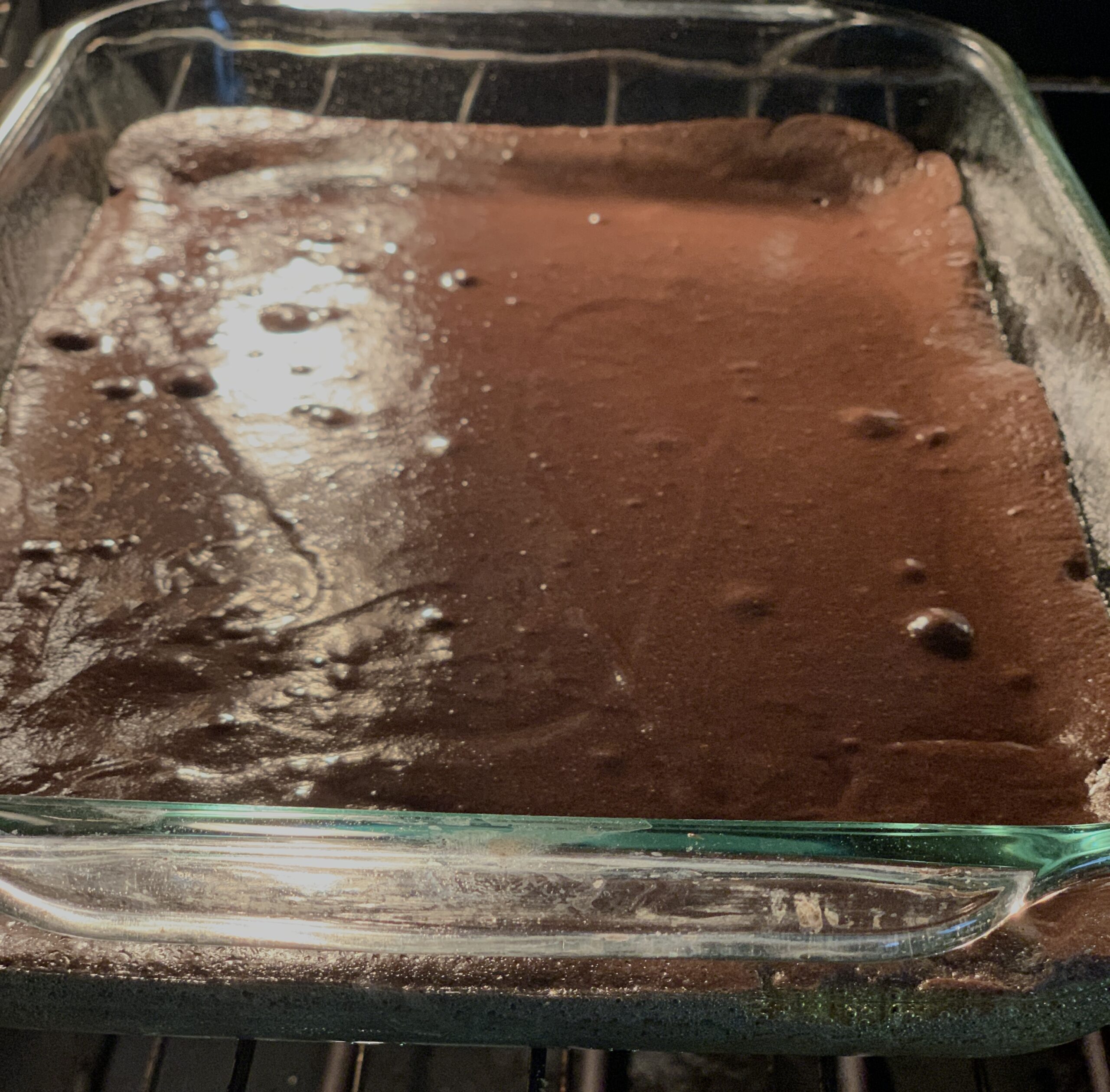 glass baking dish of brownie batter in the oven