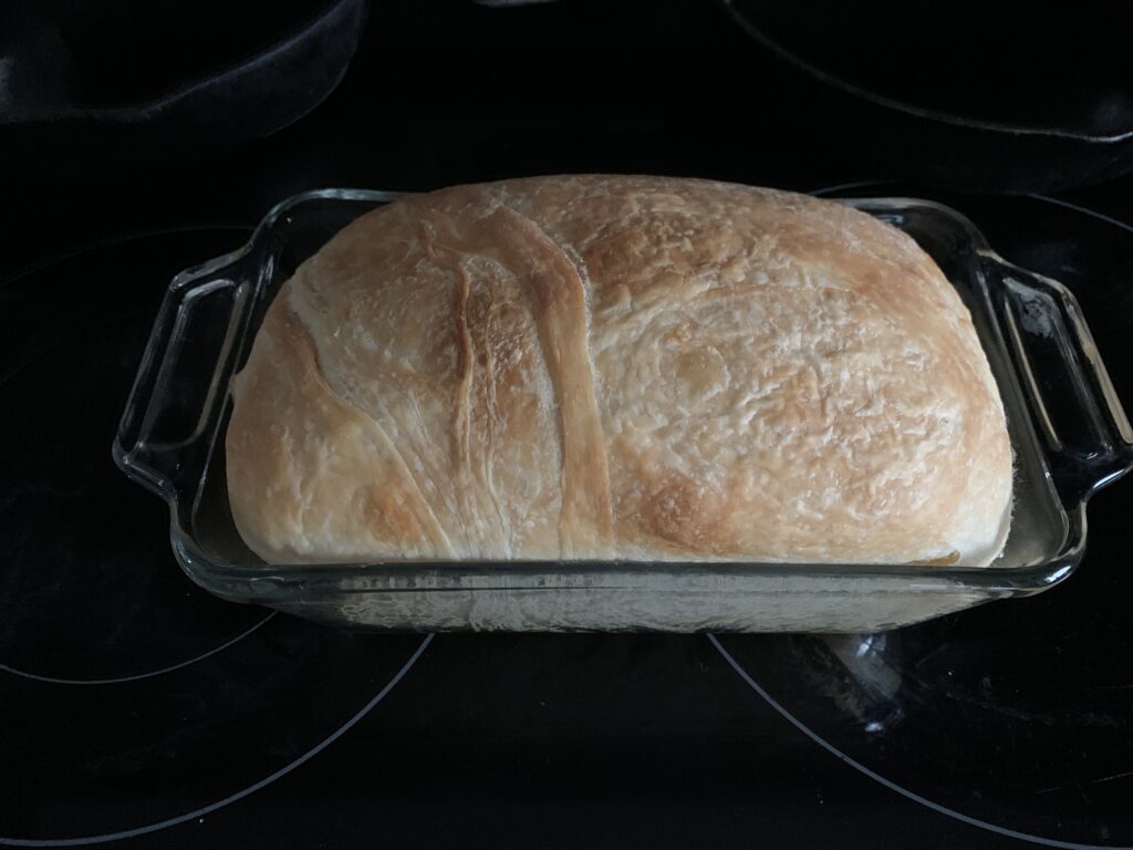 no yeast sourdough bread sitting on a black counter in a clear glass loaf pan