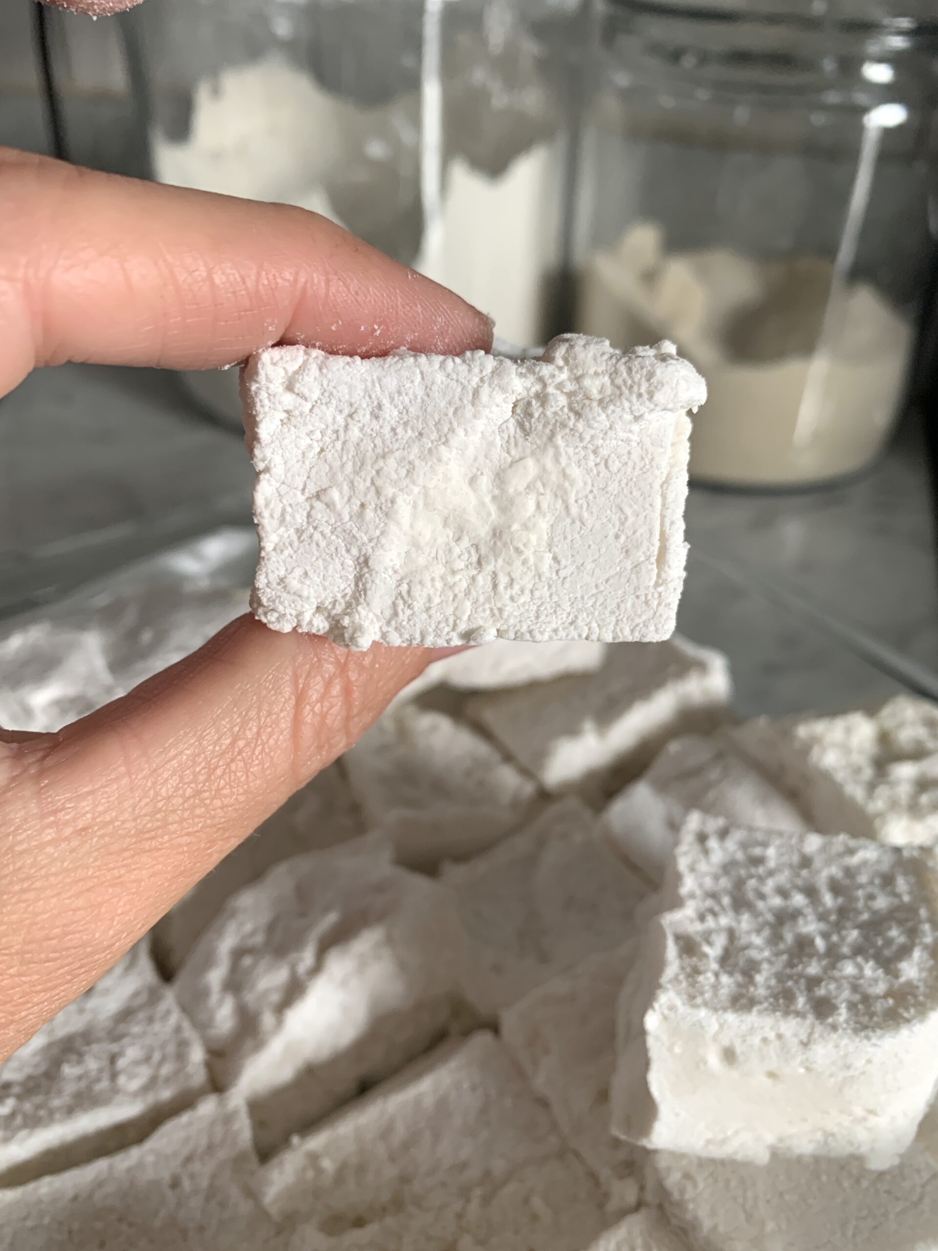 2 fingers holding a square cut marshmallow