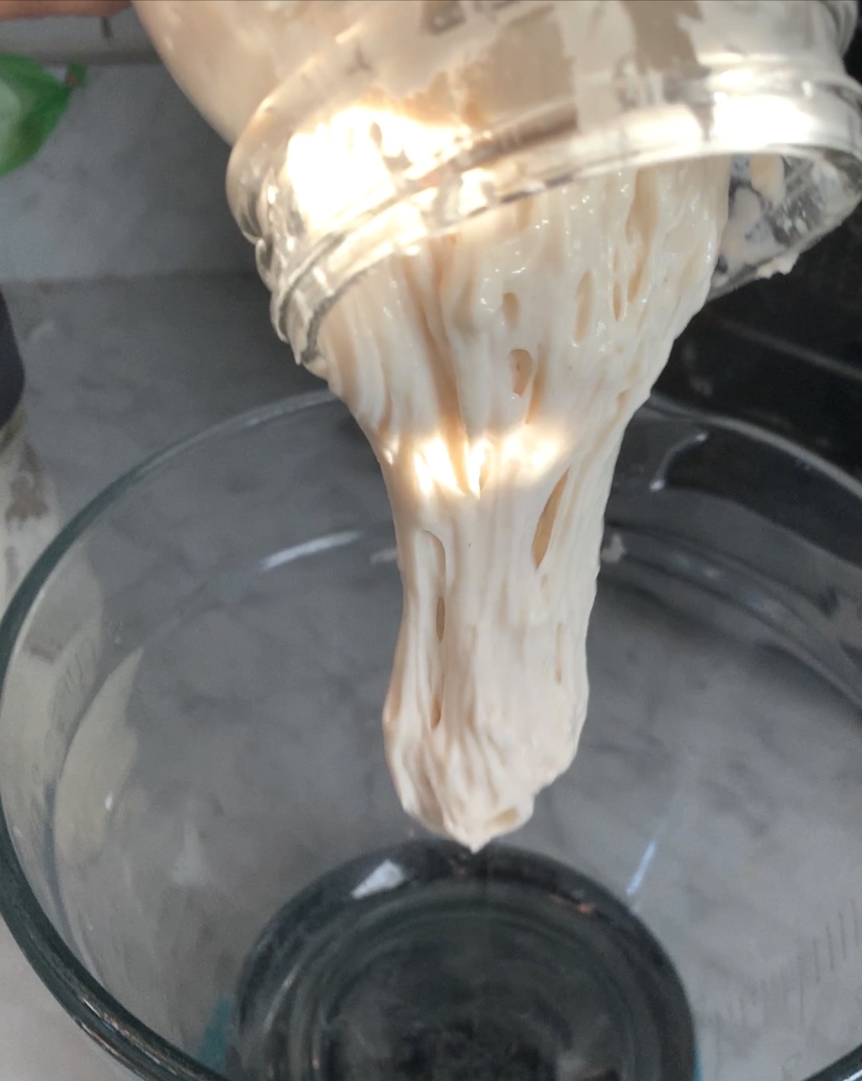 active sourdough falling out of a jar into a clear clear bowl
