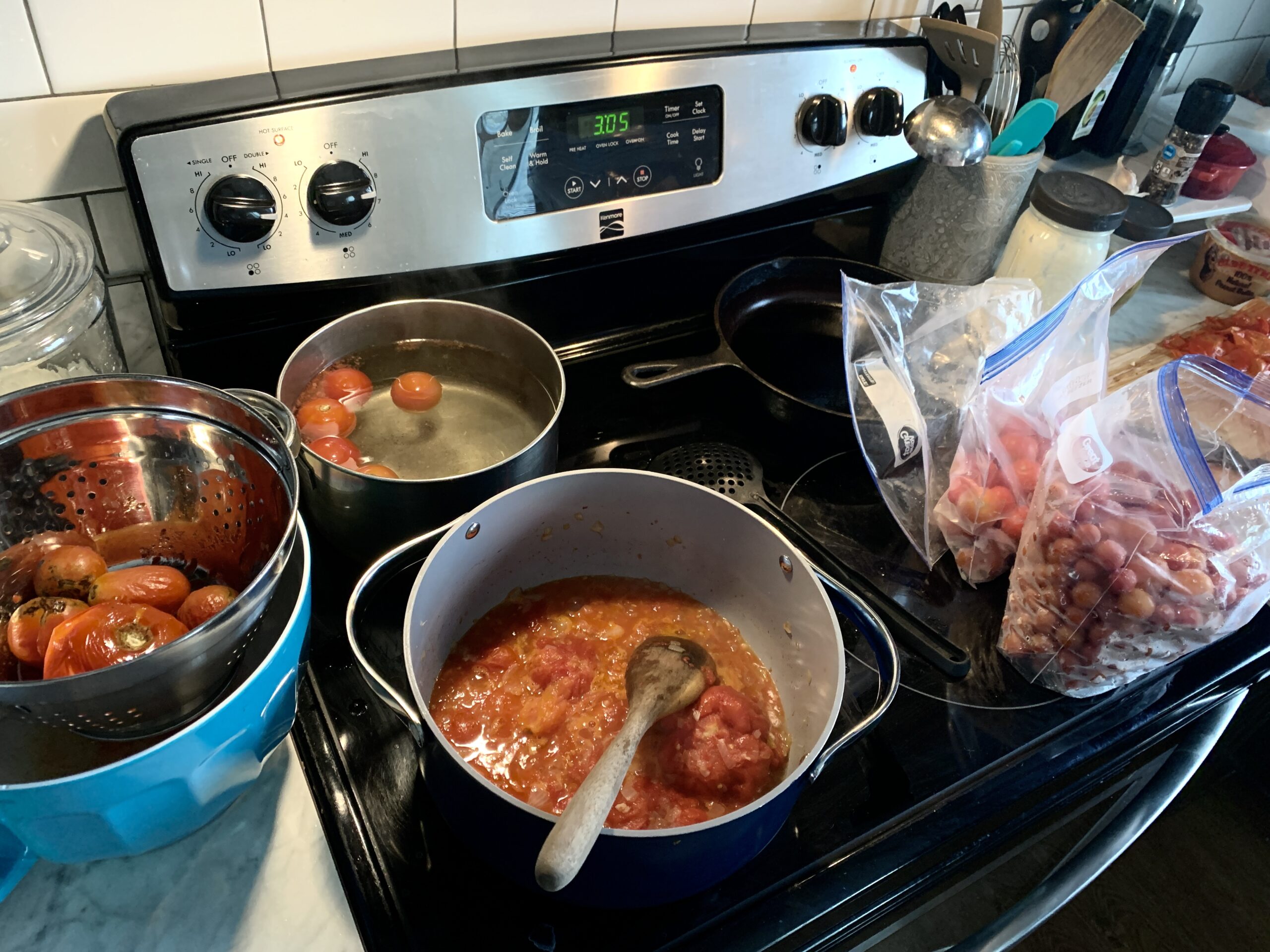 stove top with two pots boiling tomatoes and making sauce in the other