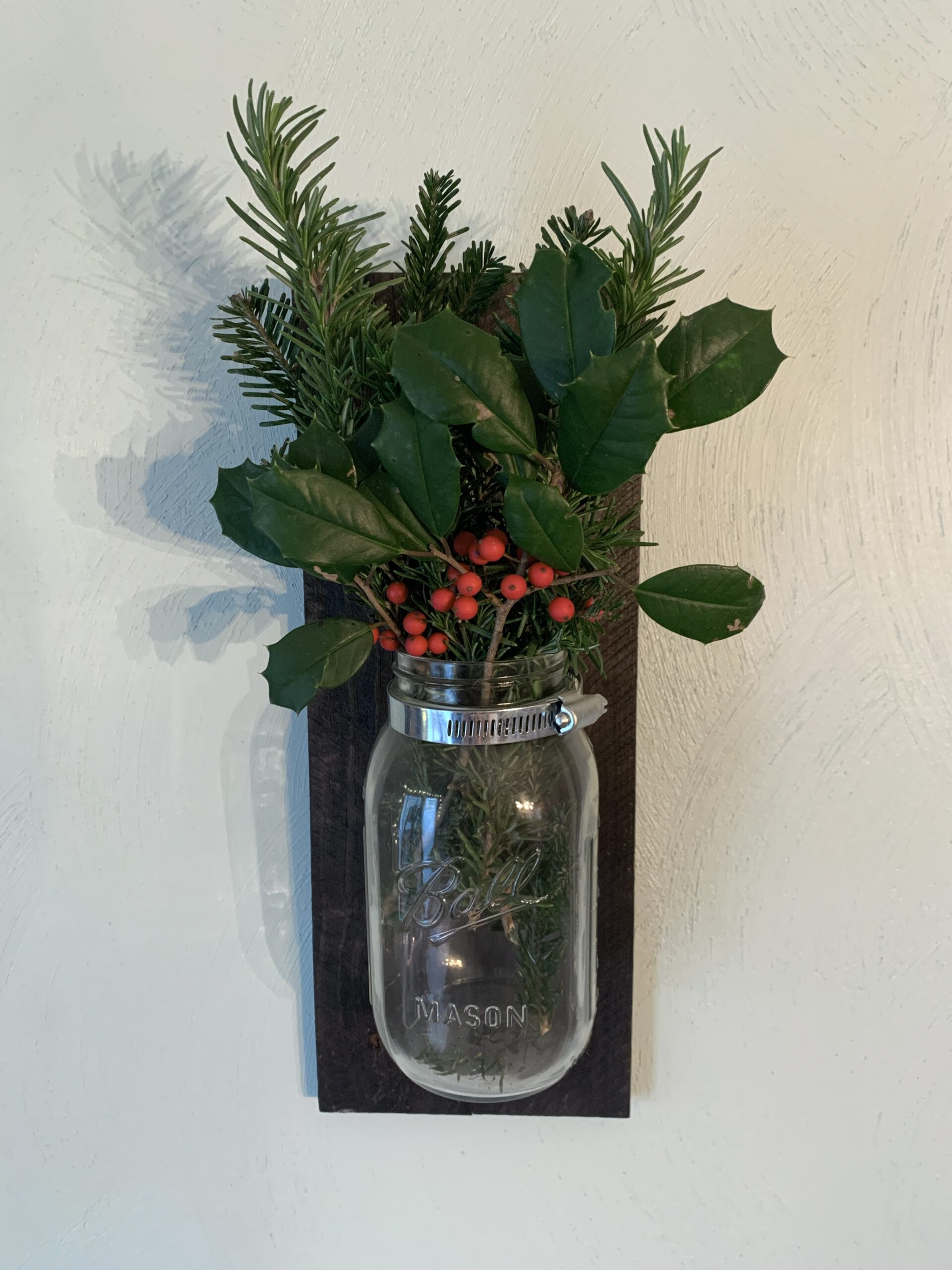 wall scone filled with evergreens and holly berries