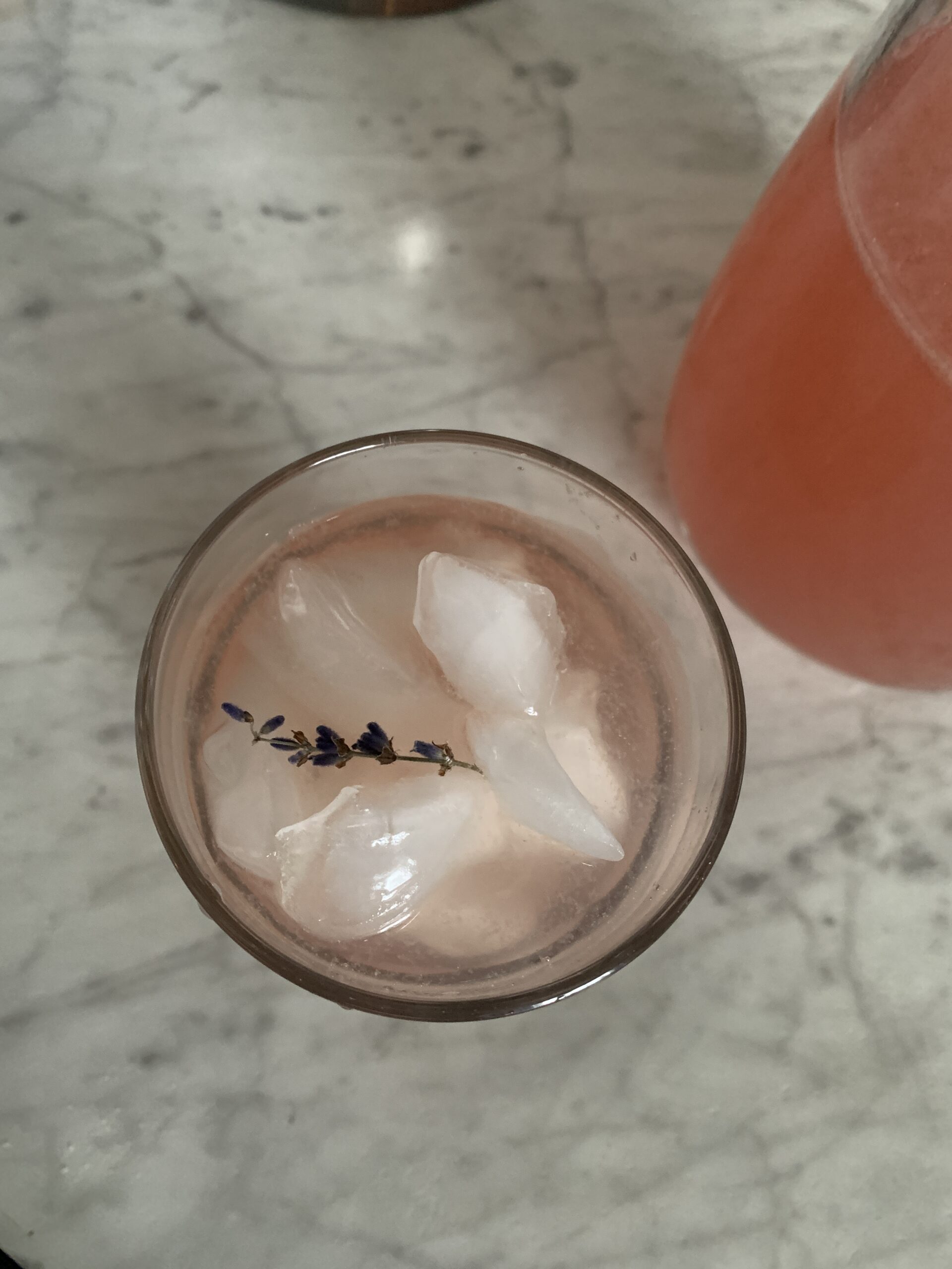 bird's eye view of a glass of lavender lemonade with a sprig of lavender on top of ice