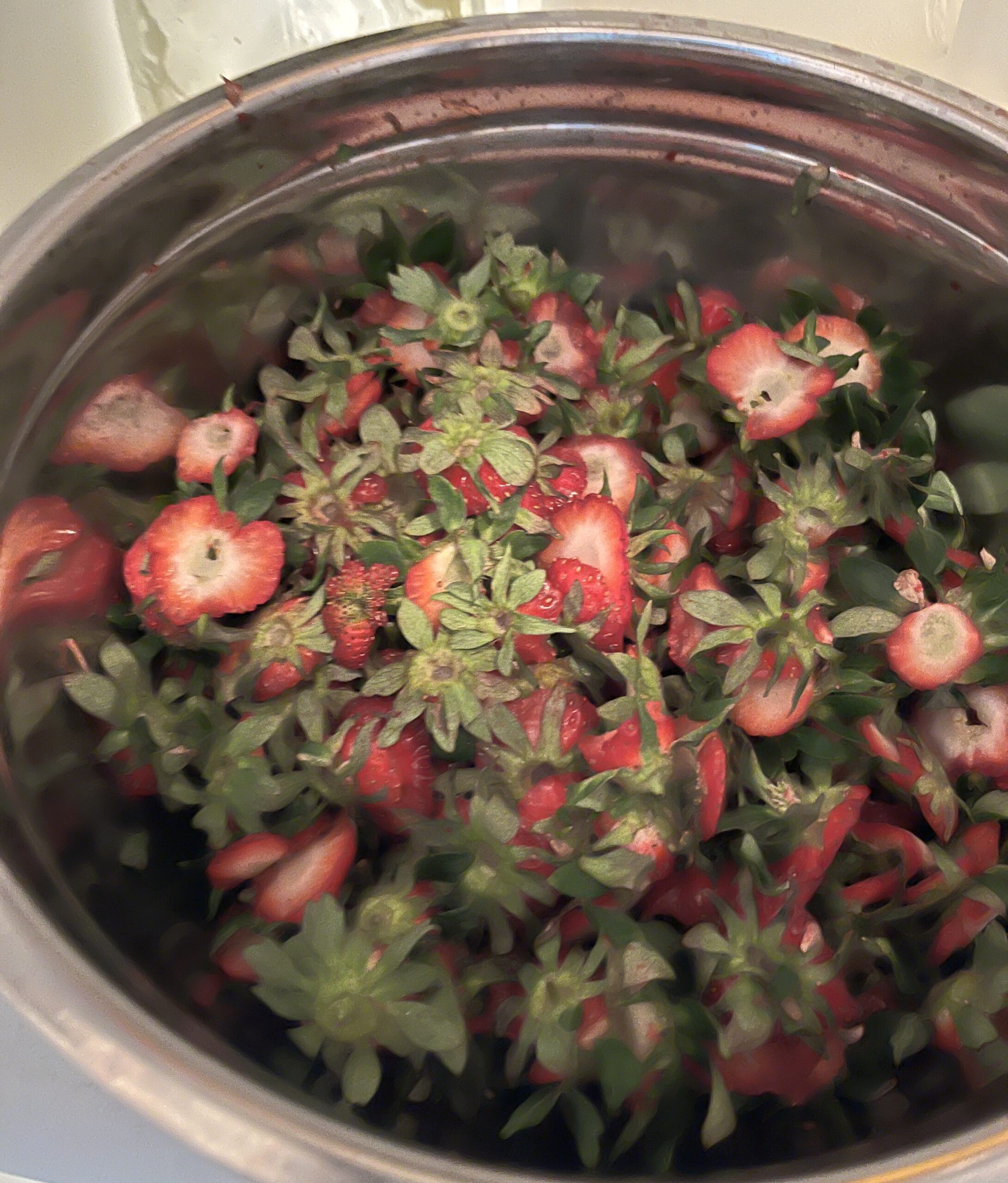 a silver bowl of strawberry tops