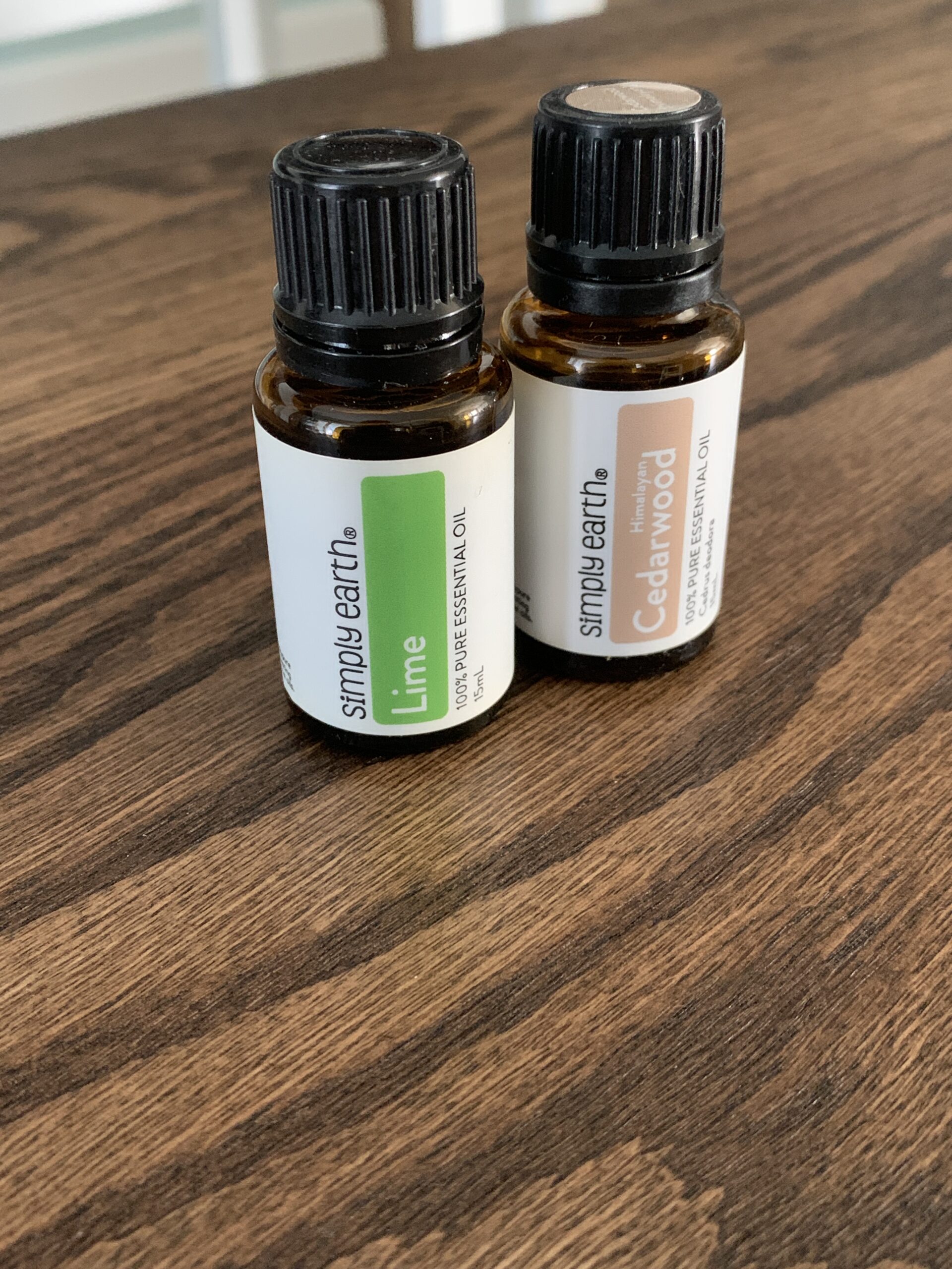 two bottles of Simply Earth essential oils sitting on a wooden table