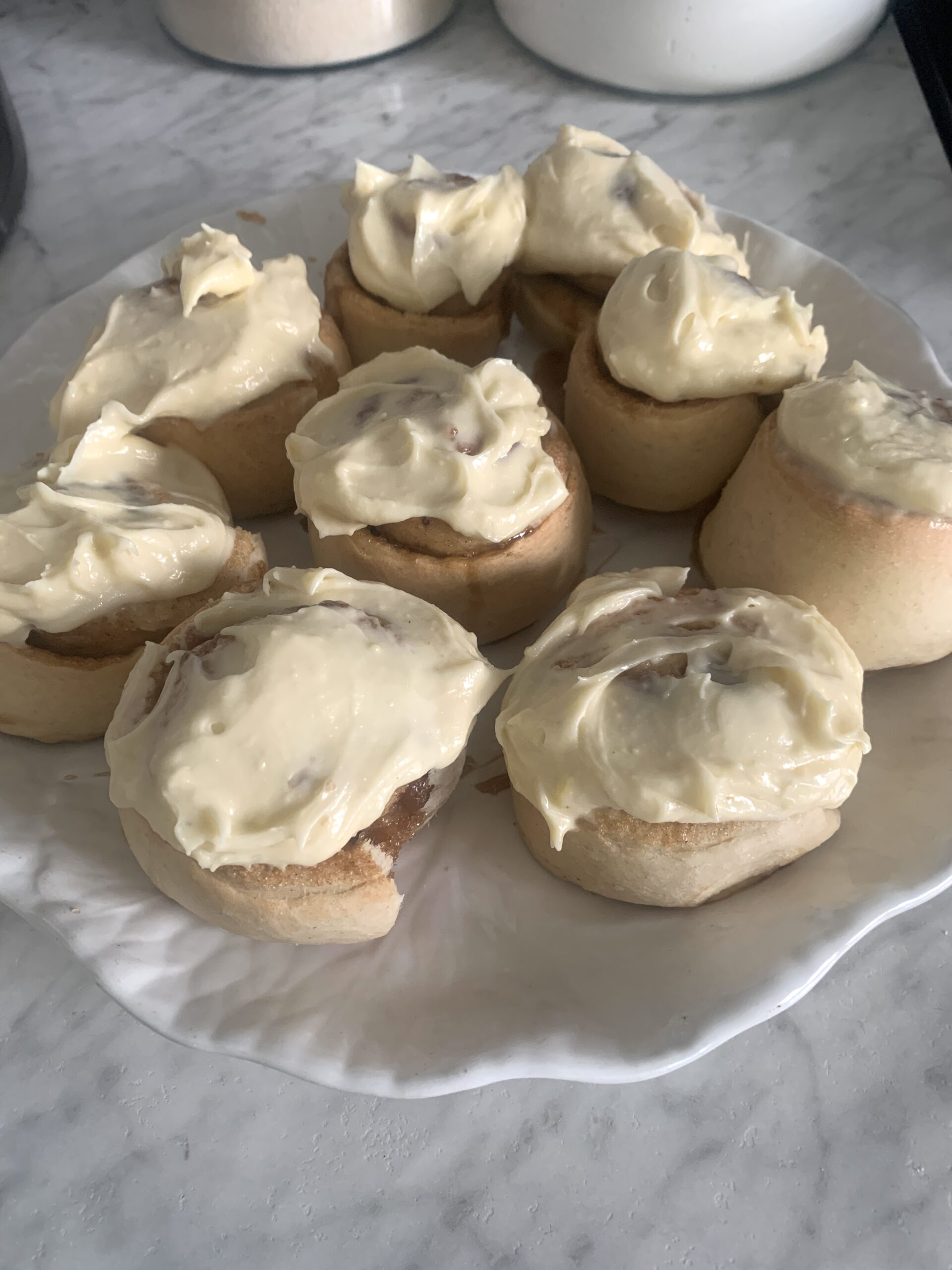 white plate of cream cheese frosting topped cinnamon rolls as a cozy winter hobby