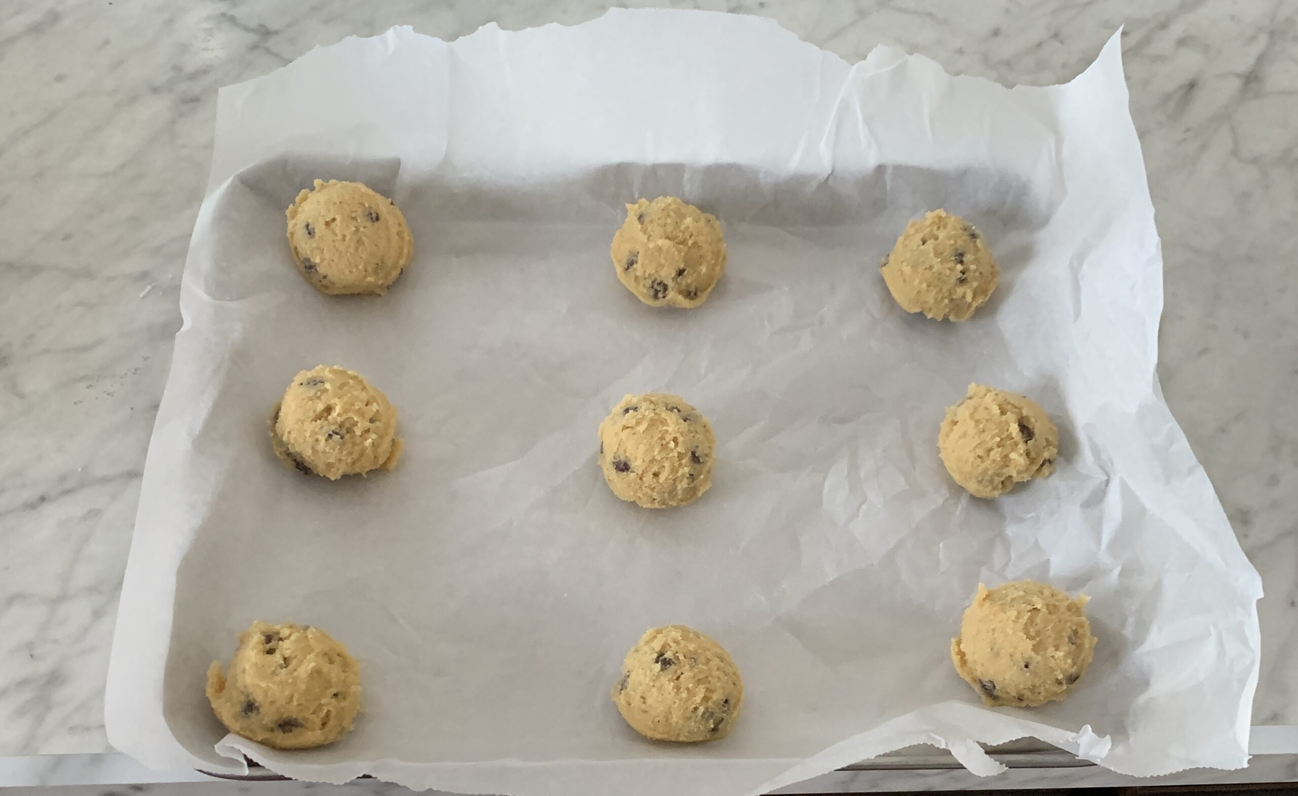 chocolate chip cookie dough balls on white parchment paper