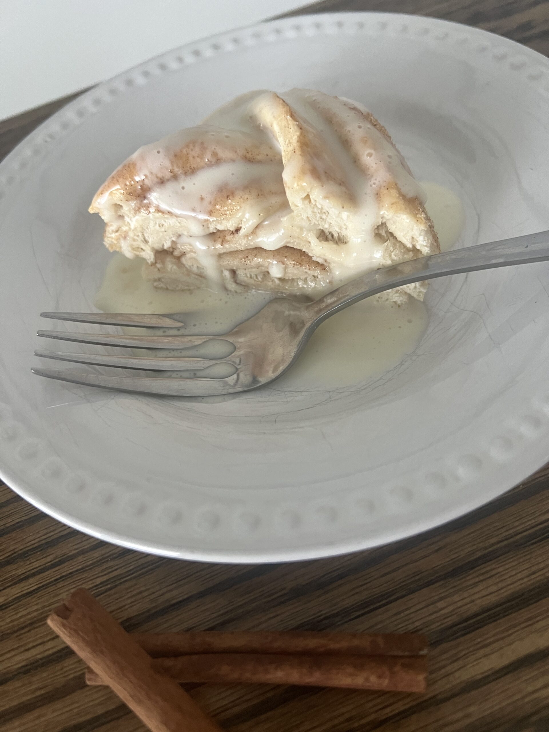 a slice of cinnamon twist on a white plate with a silver fork