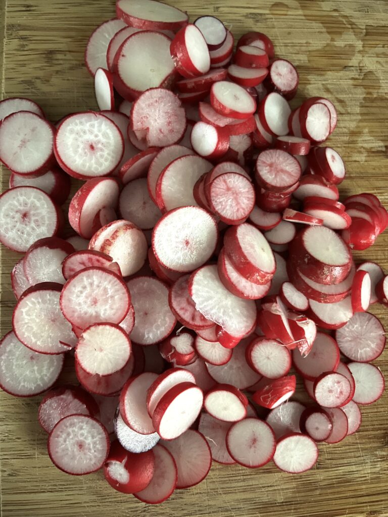 sliced cherry belle radish on a wooden cutting board