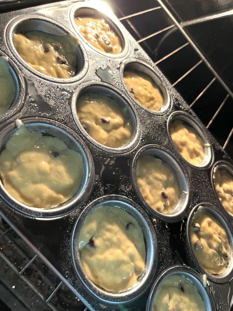 stainless steel muffin pan with banana muffin batter inside an oven