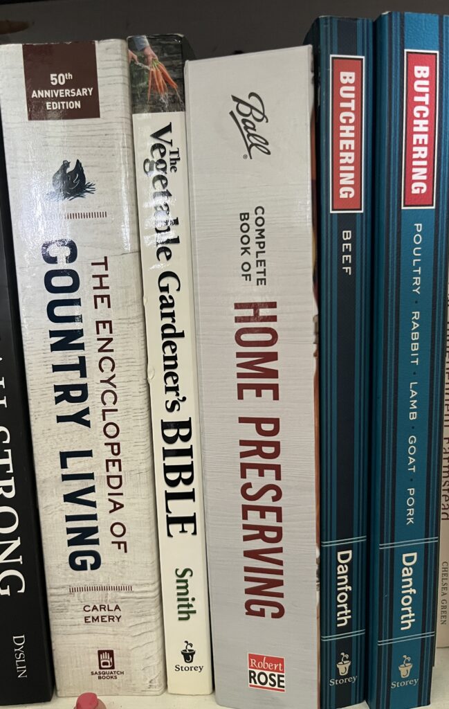 books on beginner homesteading skills standing up on a shelf