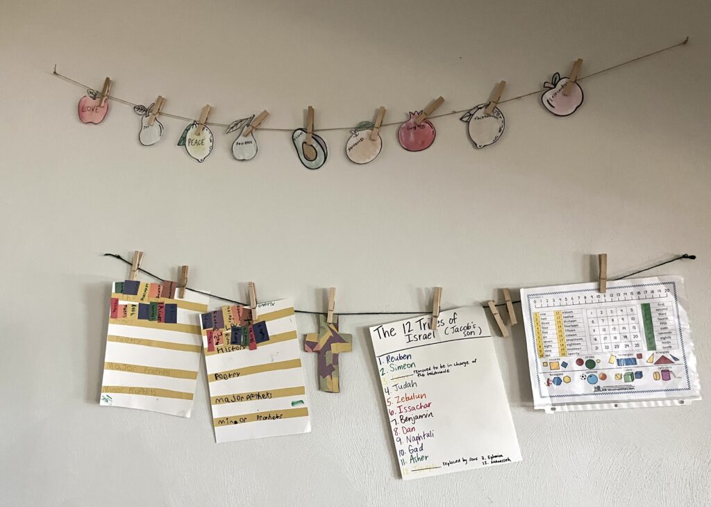 two twine strings on a wall displaying school work and the 9 Fruit of the Spirit water color