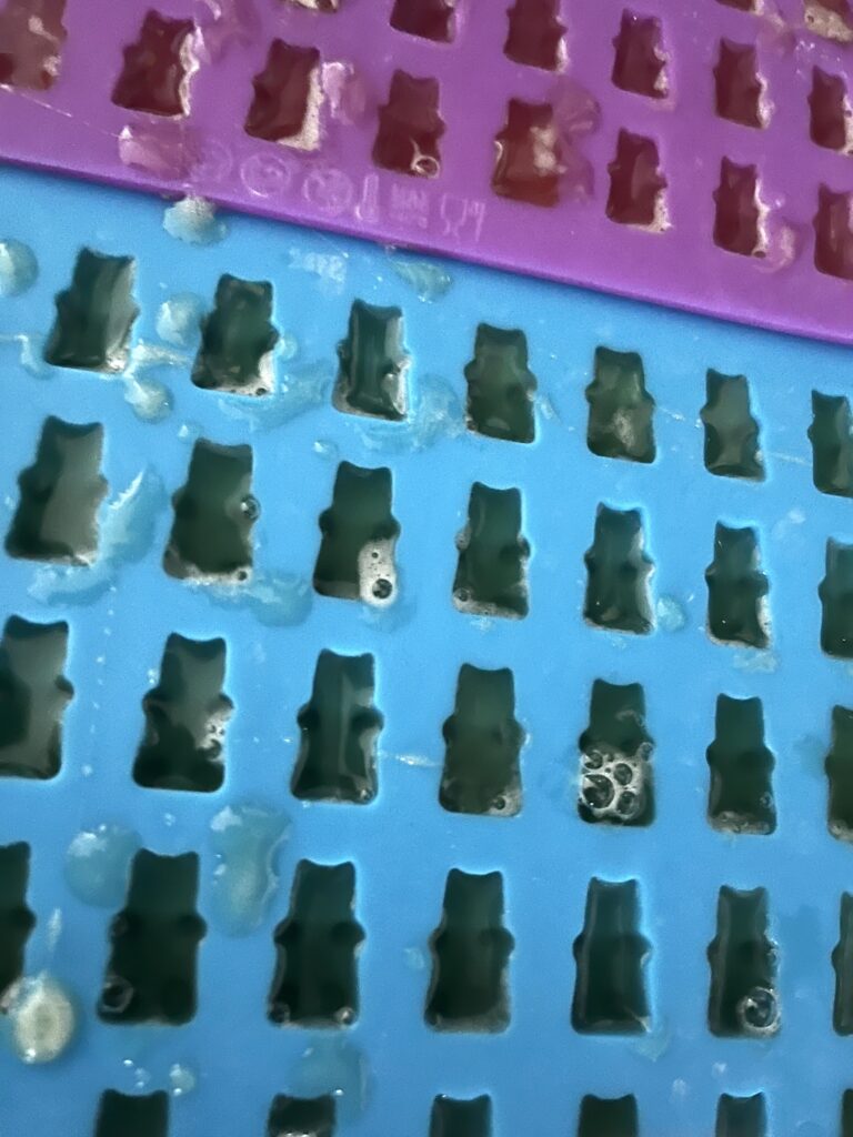 blue and purple gummy bear molds with liquified gummy candy
