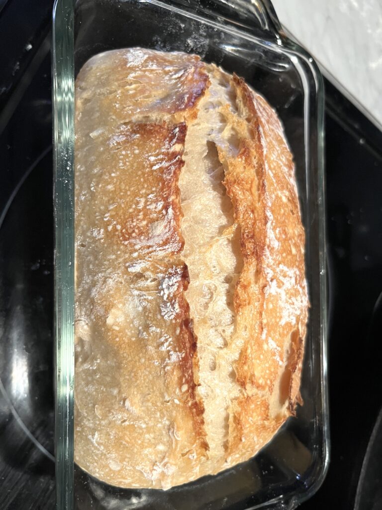 loaf of no-fuss sourdough sandwich bread in a glass loaf pan