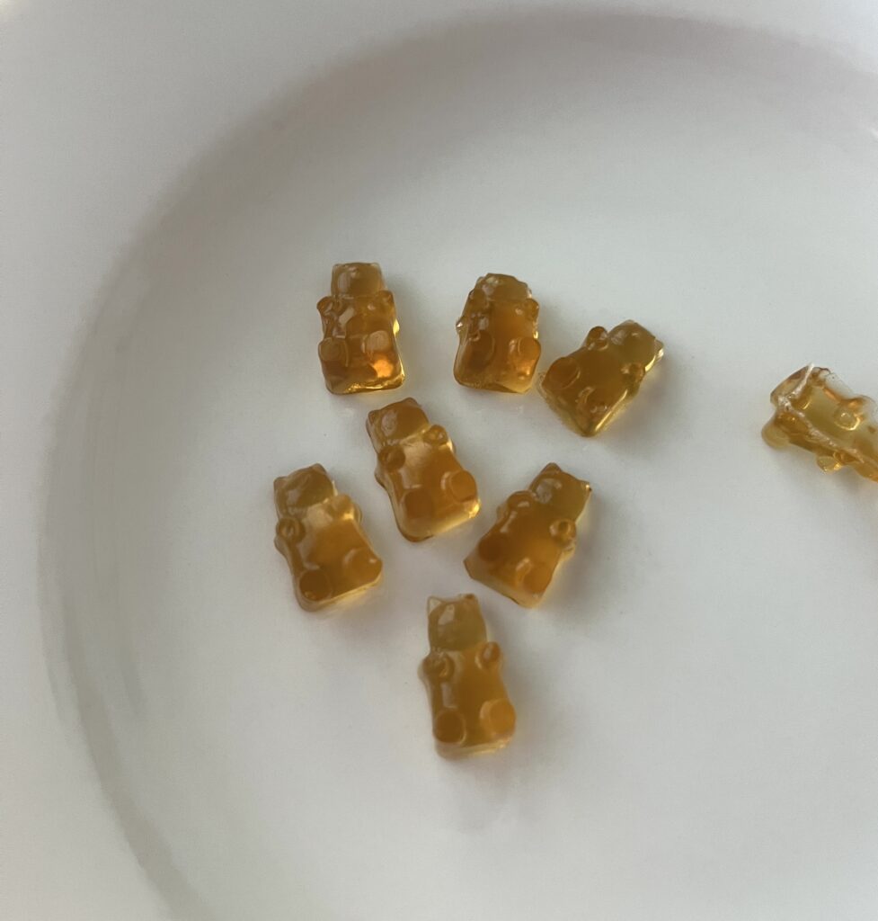 8 golden gummy candies sitting on a white plate