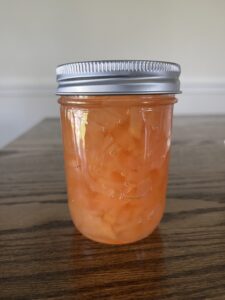 a single pint jar of pear jam sitting on a wooden table