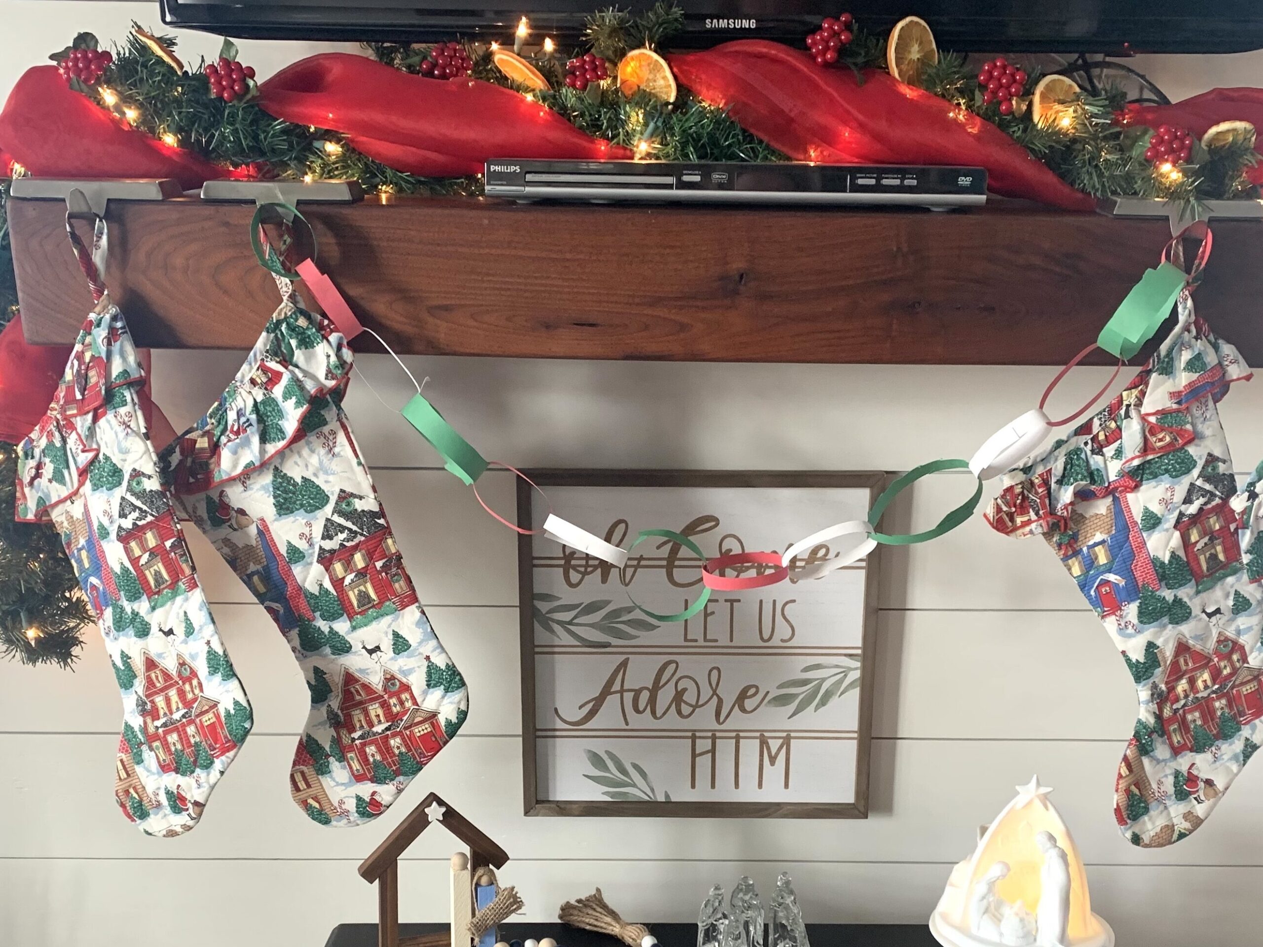 wooden mantle over lit black gas stove decorated for Christmas with greenery and orange slices are a one stop Christmas crafts idea by Johnson Home NC blog author
