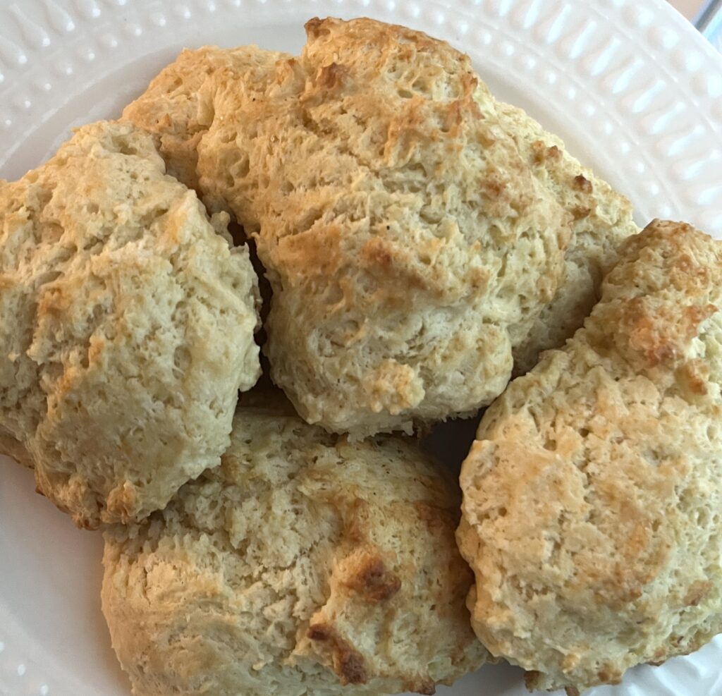 a white plate of golden brown drop biscuits piled up