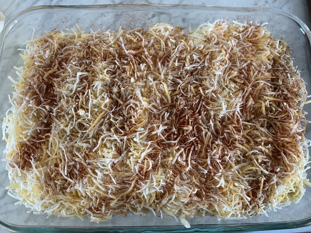 mix of uncooked mac and cheese with milk, butter, cheeses, and spices on top