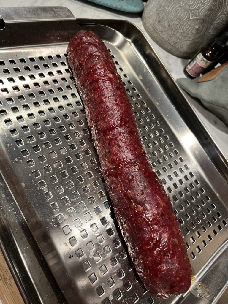 pepperoni meat stick on a stainless steel grilling rack