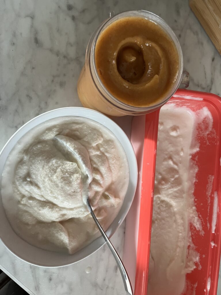 white bowl of ice cream, orange colored rectangle ice cream container, glass of peach puree sitting on a marble counter top