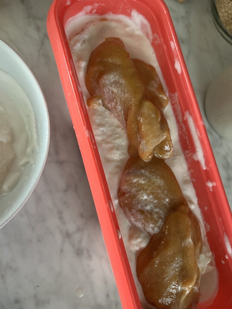 orange rectangle ice cream container with vanilla ice cream and peach puree dolloped on top
