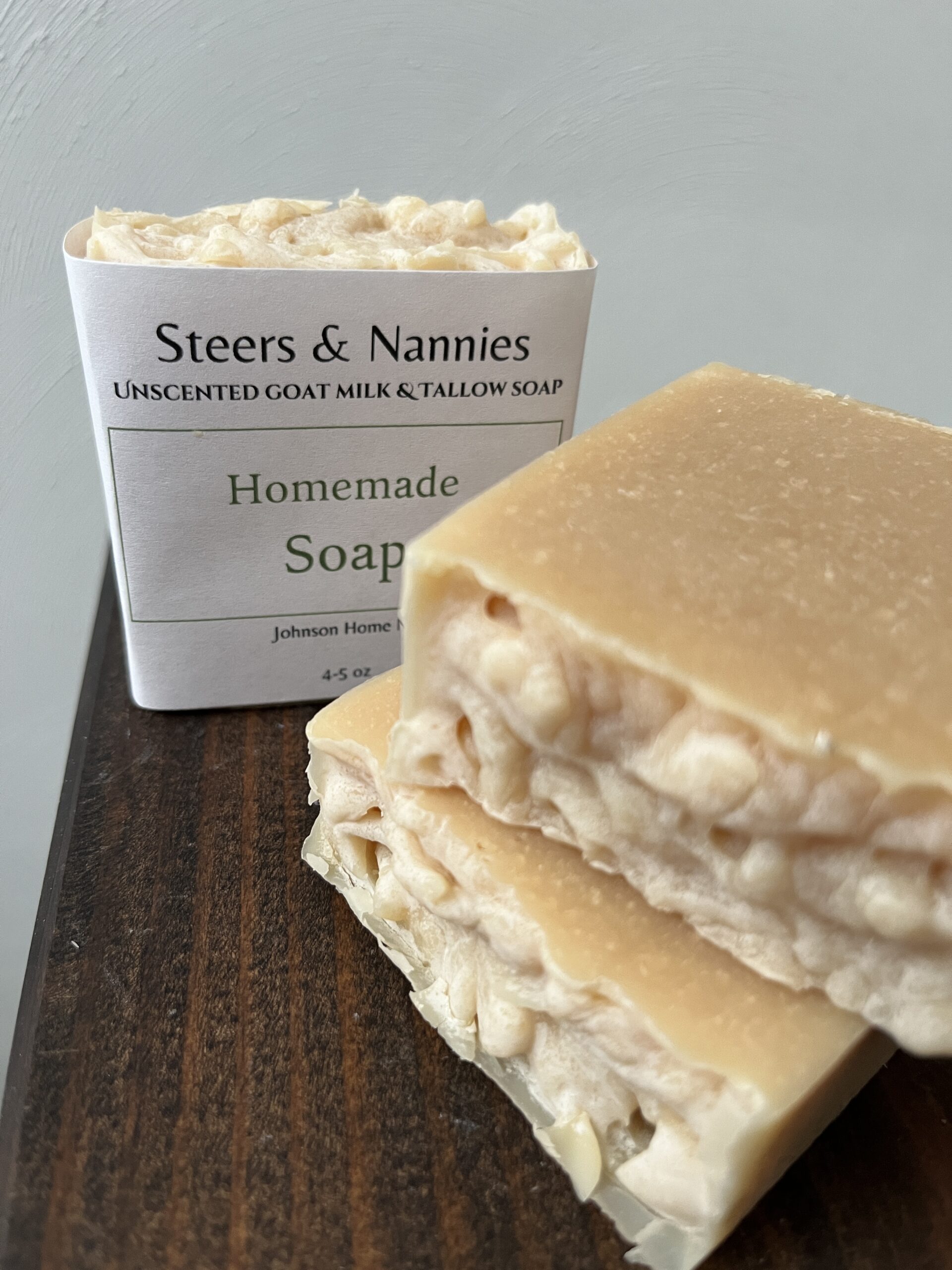 three bars of tallow and goats milk soap bars sitting on a wooden table with a white background