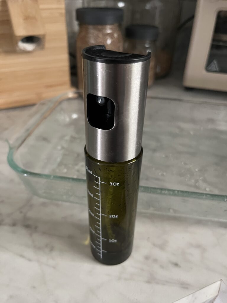 bottle of spray avocado oil in front of a clear baking pan