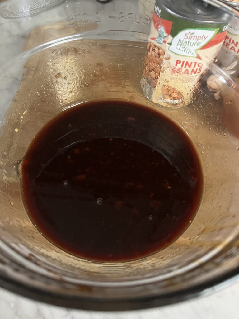 clear mixing bowl of dark brown baked beans sauce